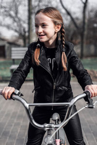 Smiling girl with bicycle at park