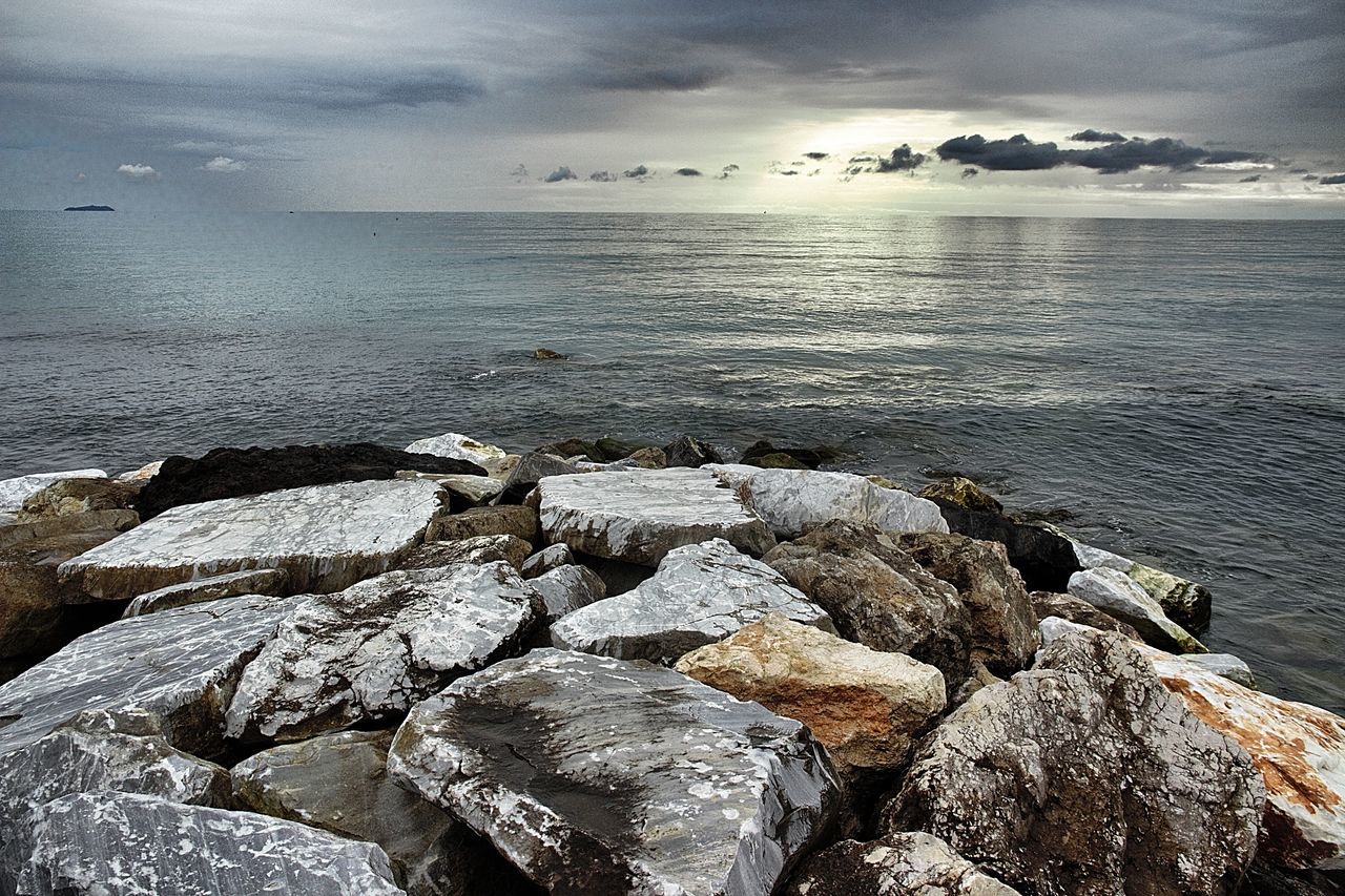 VIEW OF CALM SEA AGAINST ROCKY LANDSCAPE