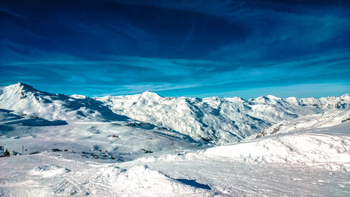 Scenic view of snowcapped mountains against blue sky