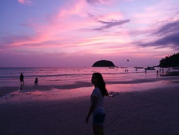 Woman on beach against sky during sunset