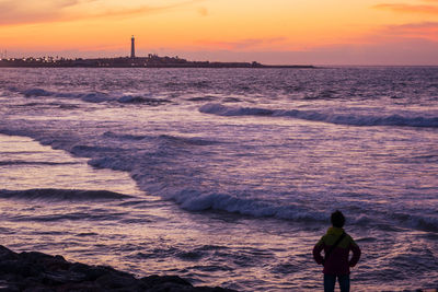 Silhouette man on beach against sky during sunset