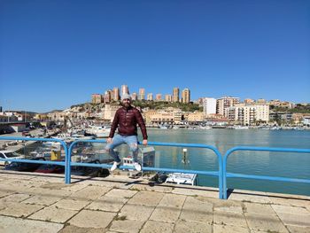 People looking at swimming pool against buildings in city