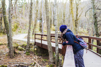 Woman leaning on footbridge during winter