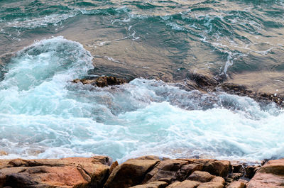 Foaming sea water hits stone beach, wave and beach, nature background concept. 