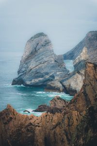 Rock formations by sea against sky