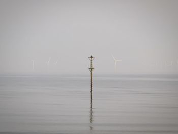 Wind turbines in sea against sky