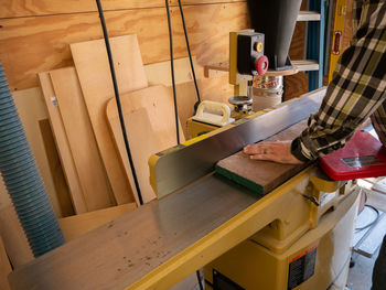 A carpenter using a joiner in his shop