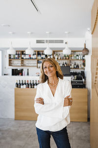 Happy businesswoman with arms crossed standing at restaurant