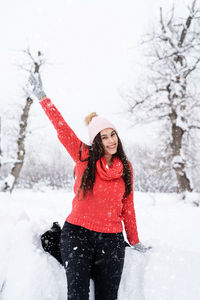 Winter season. portrait of a beautiful smiling woman in red sweater and hat in snowy park 
