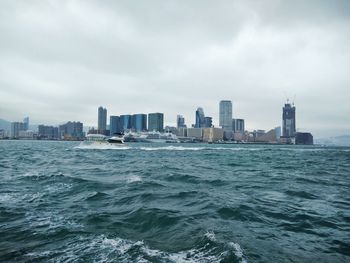 River and buildings against cloudy sky in city