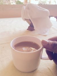 Close-up of woman holding coffee cup on table