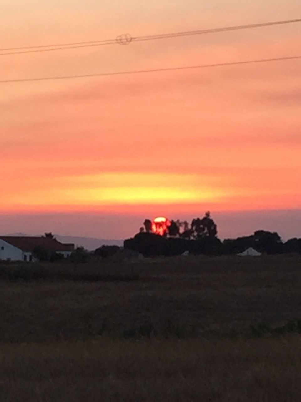 sunset, silhouette, scenics, house, tranquil scene, architecture, built structure, tranquility, orange color, beauty in nature, building exterior, sky, dramatic sky, nature, illuminated, romantic sky, majestic, cloud - sky, outdoors, non-urban scene, vibrant color, atmosphere, sea, remote, power line