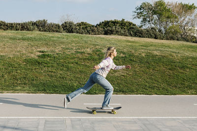 Mid adult woman skateboarding on road