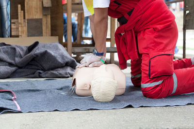 Low section of paramedic performing cpr on dummy