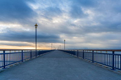 Road leading towards bridge against sky