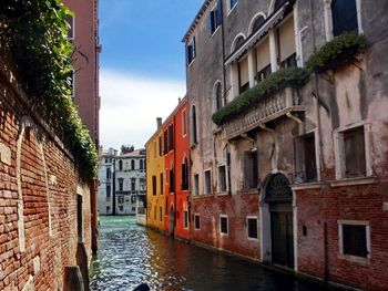 Canal amidst buildings against sky
