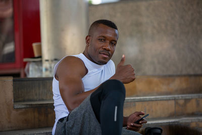 Young man looking away while sitting outdoors