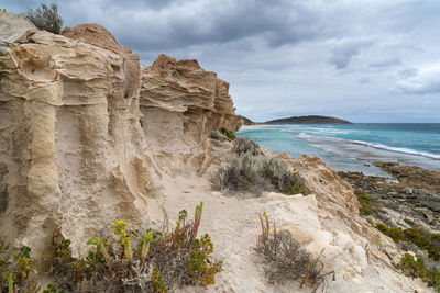 Rock formation on beach against sky