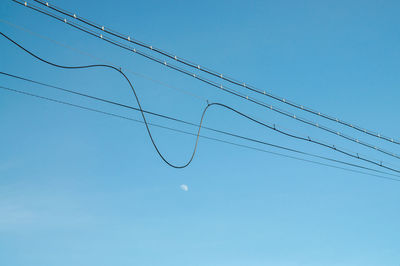 Low angle view of power lines against blue sky