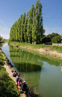 Scenic view of canal by trees against sky