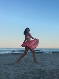 Full length of woman on beach against sky during sunset