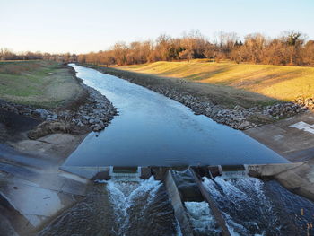 Scenic view of river amidst field against sky during winter