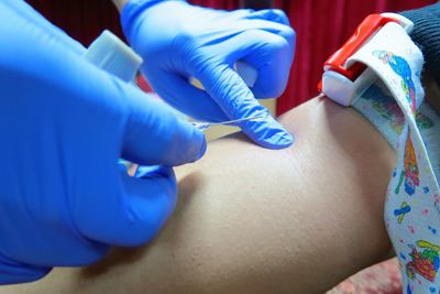 Cropped hands of doctor injecting patient in hospital