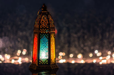 Lantern with lights decorating for islamic new year put at window with rain drop at background.