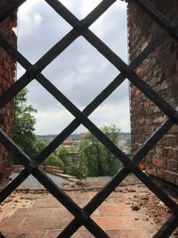 Close-up of chainlink fence against sky seen through window