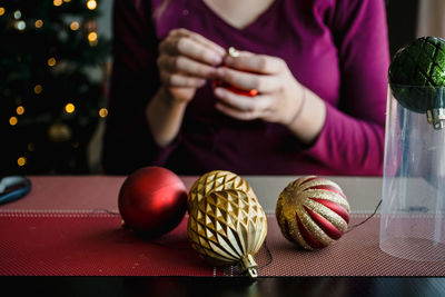 Midsection of woman making christmas baubles on table