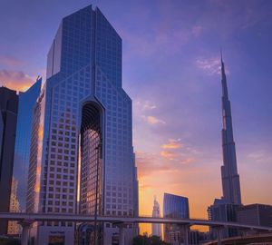 Low angle view of skyscrapers against cloudy sky