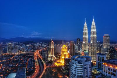 Illuminated cityscape against blue sky