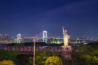 Illuminated bridge over city at night