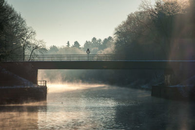 Bridge over river against sky at sunset