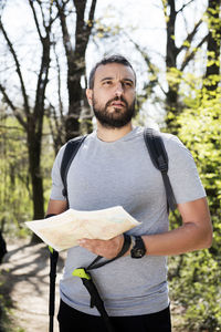 Hiker holding map while standing in forest