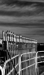 Metal fence on beach against sky