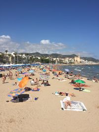 People relaxing on beach against sky