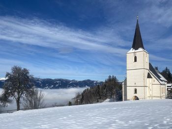 Church by building against sky during winter