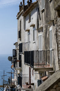 Residential buildings by sea against sky