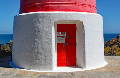 Red arrow sign on building by sea against sky