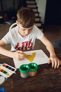 Rear view of boy looking at table at home