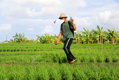 Full length of young man standing on field against sky