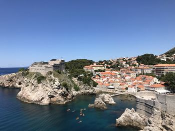 Townscape by sea against clear blue sky