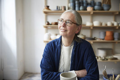 Thoughtful mature woman sitting in pottery class