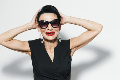 Portrait of young woman wearing sunglasses against white background