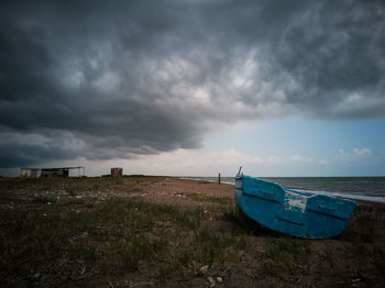 Boat moored on beach against sky