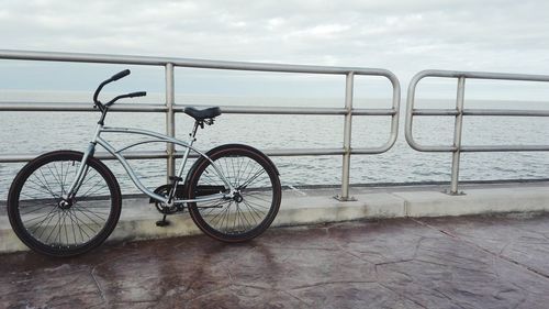 Bicycle by railing against sea