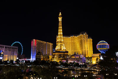 Illuminated buildings in city against clear sky at night