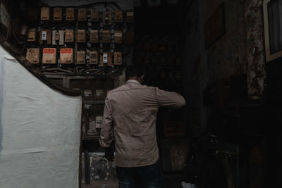 Rear view of man working on alley amidst buildings