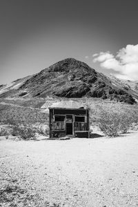 Abandoned shack on field by mountain against sky